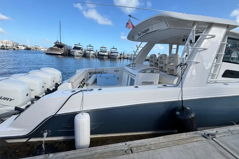 Slide: The Image of 2017 Boston Whaler 420 Outrage docked, featuring multiple outboard engines and spacious seating. - 12