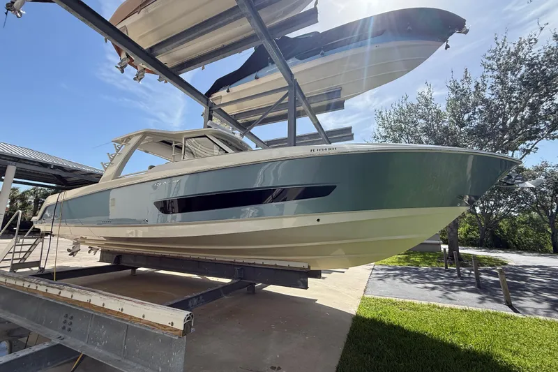 Slide: The Image of 2017 Boston Whaler 420 Outrage boat on a lift under clear blue sky. - 2