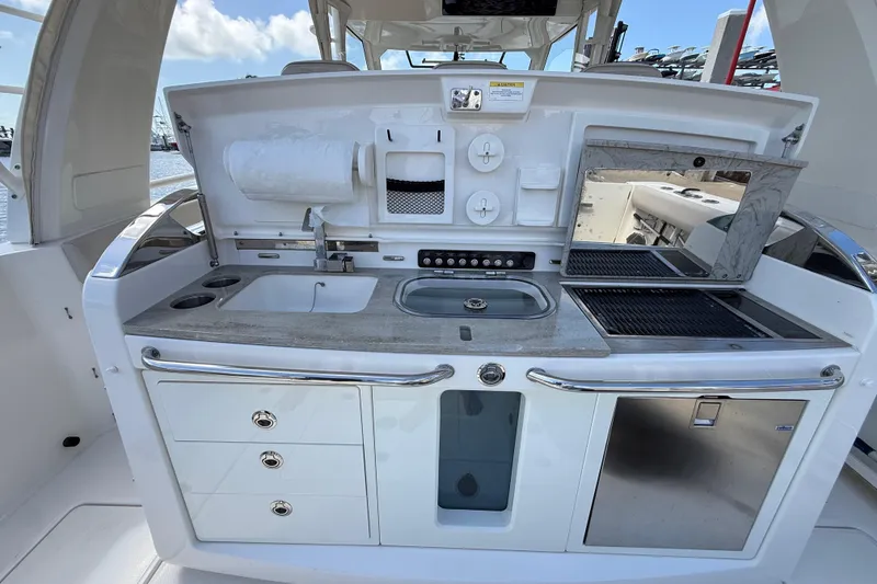 Slide: The Image of 2017 Boston Whaler 420 Outrage boat kitchen with sink, grill, and storage compartments. - 26