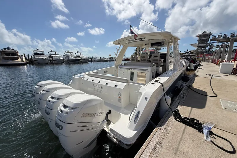 Slide: The Image of 2017 Boston Whaler 420 Outrage docked, featuring triple Mercury engines, under a sunny sky. - 41