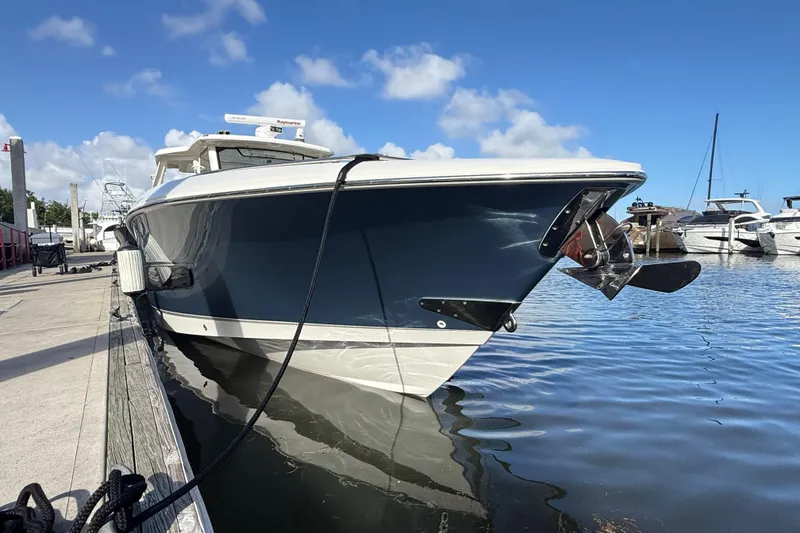Slide: The Image of 2017 Boston Whaler 420 Outrage docked, reflecting on calm water under a clear blue sky. - 8