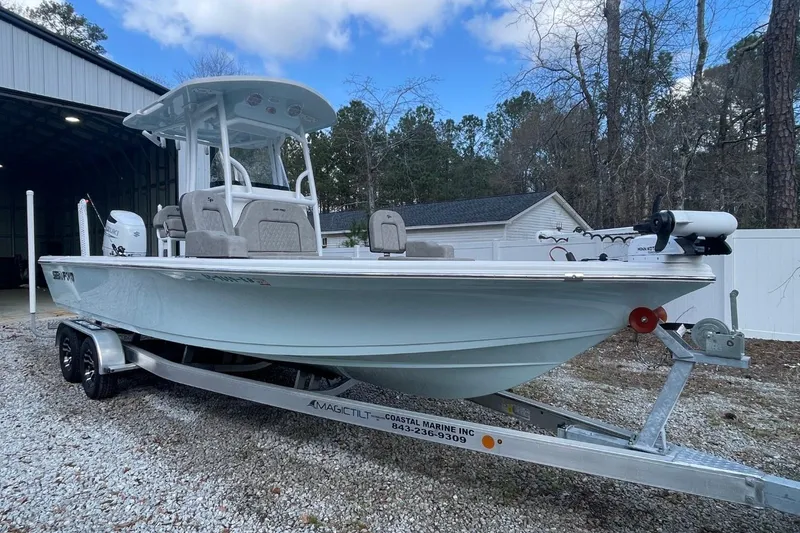 The Image of 2023 Sea Pro 248 Bay boat on trailer, parked outdoors near a garage. - 0