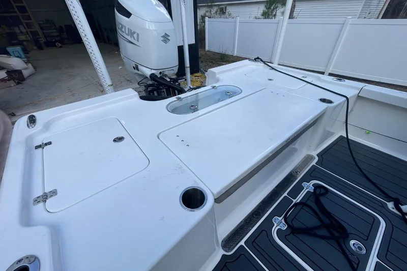 Slide: The Image of 2023 Sea Pro 248 Bay boat deck with Suzuki outboard motor in a garage setting. - 10