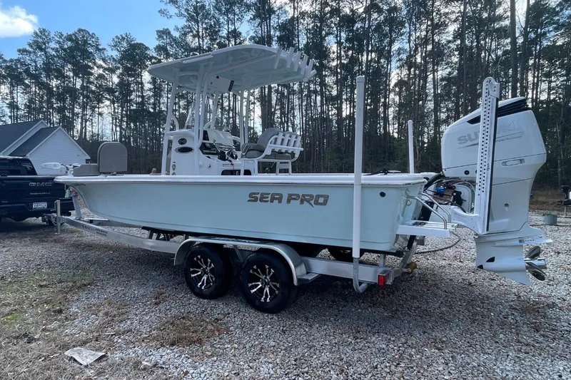 Slide: The Image of 2023 Sea Pro 248 Bay boat on trailer, parked outdoors near trees. - 2