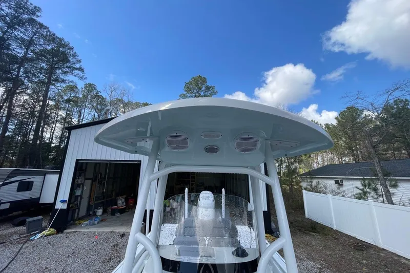 Slide: The Image of 2023 Sea Pro 248 Bay boat with T-top, parked outdoors under blue sky. - 23
