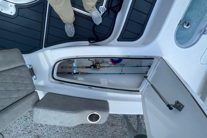 Slide: The Image of 2023 Sea Pro 248 Bay boat interior with open storage compartment and fishing rods. - 24