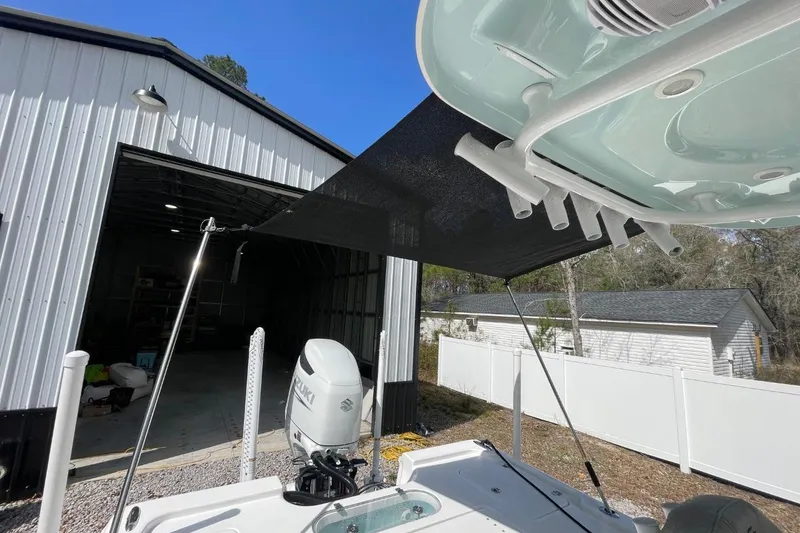 Slide: The Image of 2023 Sea Pro 248 Bay boat with sunshade, parked near a metal building. - 35