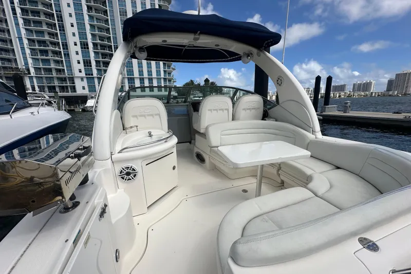 Slide: The Image of 2008 Sea Ray 340 Sundancer yacht interior with seating and table, docked near modern buildings. - 45