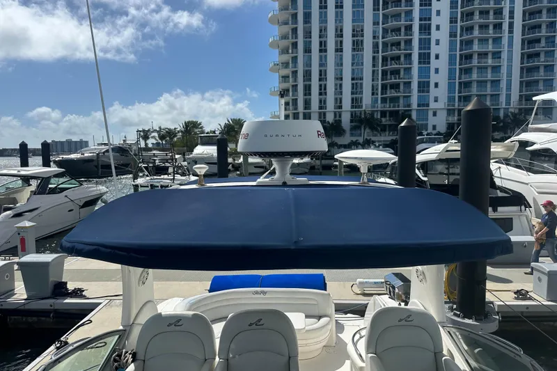 Slide: The Image of 2008 Sea Ray 340 Sundancer docked at marina with blue canopy and cityscape background. - 77