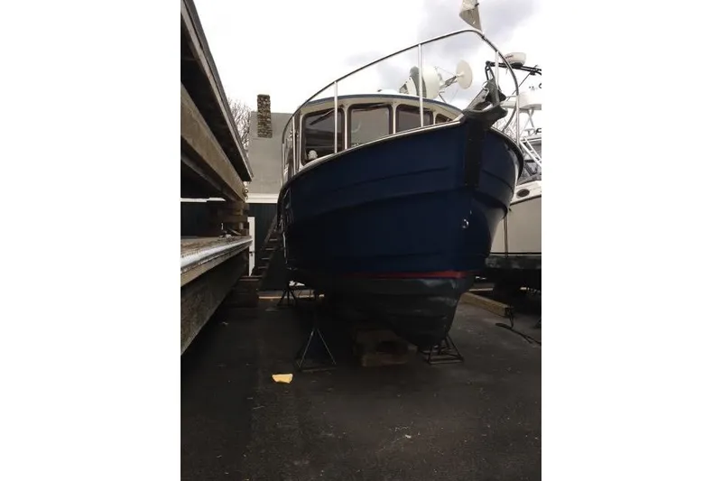 Slide: The Image of 2007 Ranger Tugs R-25 SC boat on dry dock, blue hull, marina setting. - 35