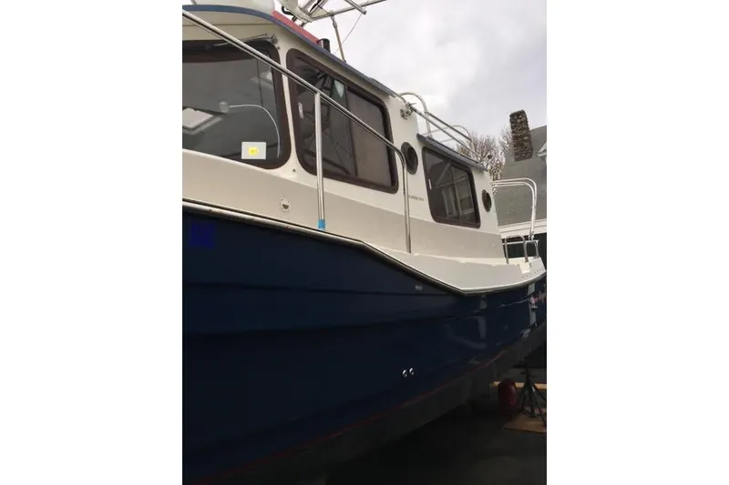 Slide: The Image of 2007 Ranger Tugs R-25 SC boat with blue hull and white cabin, docked outdoors. - 37