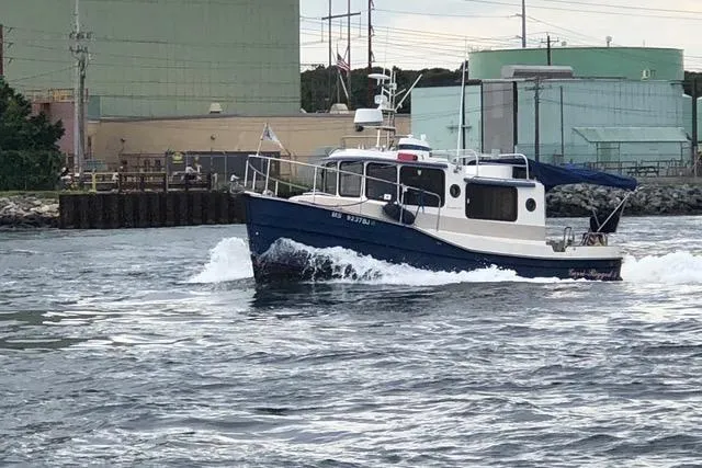 The Image of 2007 Ranger Tugs R-25 SC cruising on water near industrial buildings. - 0