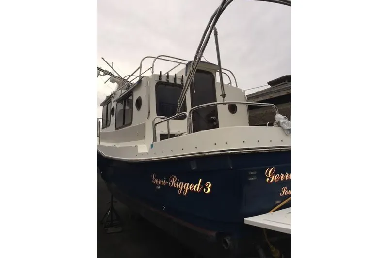 Slide: The Image of 2007 Ranger Tugs R-25 SC boat with blue hull and white cabin, docked outdoors. - 22