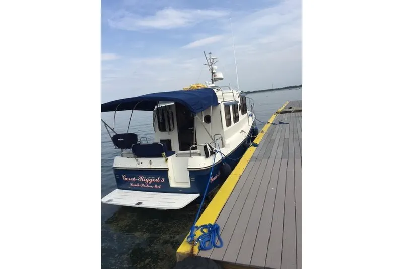 Slide: The Image of 2007 Ranger Tugs R-25 SC docked, featuring blue canopy and white hull. - 4
