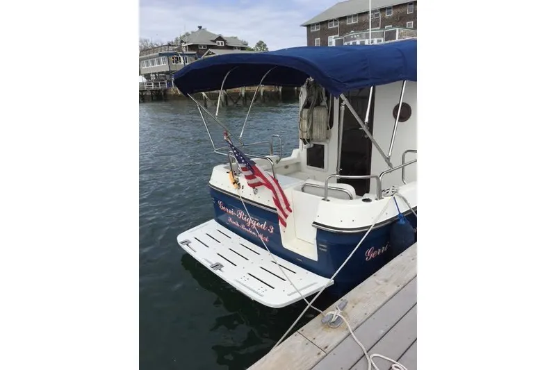 Slide: The Image of 2007 Ranger Tugs R-25 SC docked, featuring blue canopy and American flag. - 5