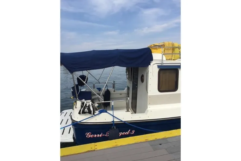 Slide: The Image of 2007 Ranger Tugs R-25 SC boat docked with blue canopy and yellow gear on top. - 6