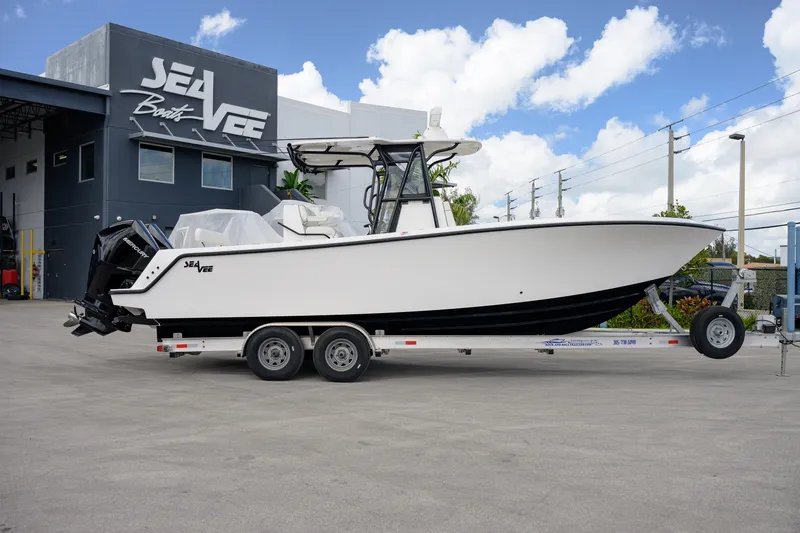 Slide: The Image of 2025 SeaVee 290B boat on trailer, parked outside SeaVee Boats facility under a blue sky. - 3