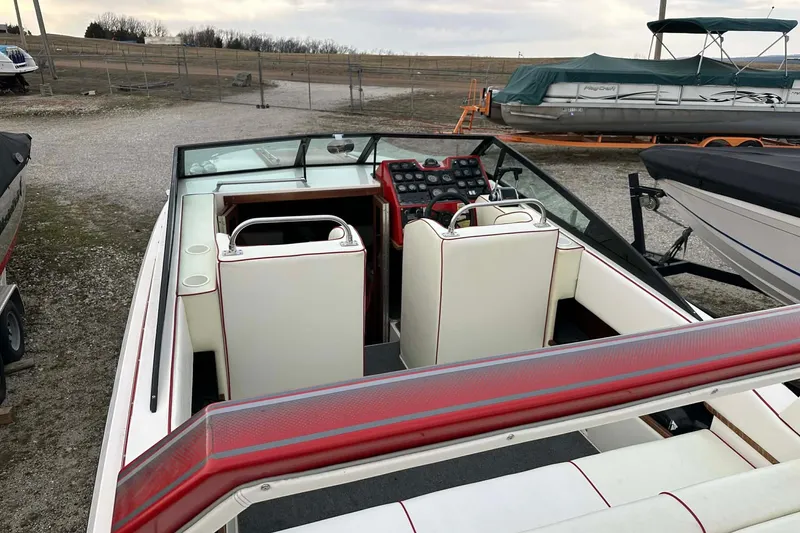 Slide: The Image of 1987 IMP 255 Eleganza boat interior with white and red seating, docked outdoors. - 12