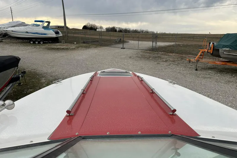 Slide: The Image of 1987 IMP 255 Eleganza boat with red and white deck, parked outdoors. - 2