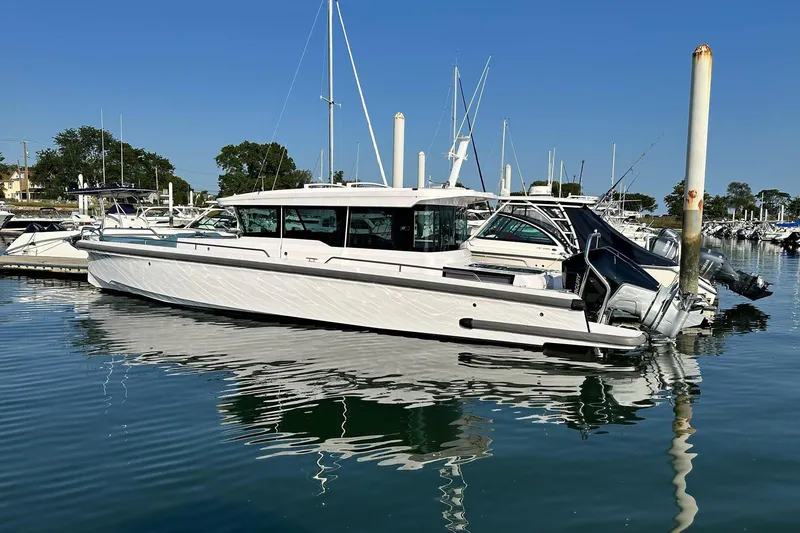 Slide: The Image of 2023 Axopar 37 XC Cross Cabin boat docked in a marina under clear blue skies. - 3