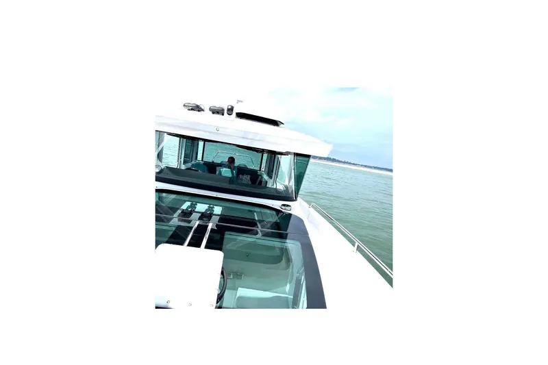 Slide: The Image of 2023 Axopar 37 XC Cross Cabin docked at a marina with scenic waterfront views. - 8