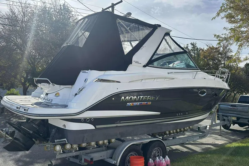 The Image of 2019 Monterey 295 Sport Yacht on trailer, black and white design, outdoor setting. - 1