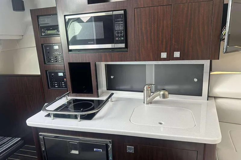 Slide: The Image of 2019 Monterey 295 Sport Yacht interior kitchen with microwave, stove, and sink. - 12