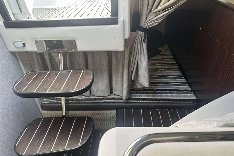 Slide: The Image of Interior of 2019 Monterey 295 Sport Yacht with wooden steps and striped bedding. - 21