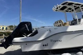 Slide: The Image of 2023 Trophy T24 CC boat with Mercury outboard motor, docked under clear blue sky. - 3