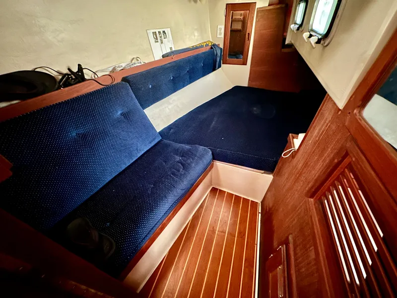 Slide: The Image of Interior of a 1987 Catalina 34 with blue cushions and wooden flooring. - 19