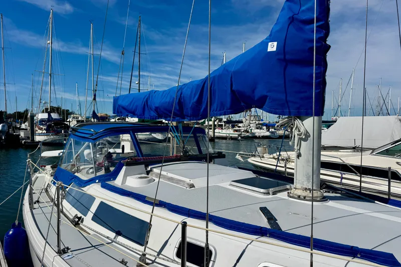 Slide: The Image of 1987 Catalina 34 sailboat docked in marina, featuring blue sail cover and clear skies. - 3