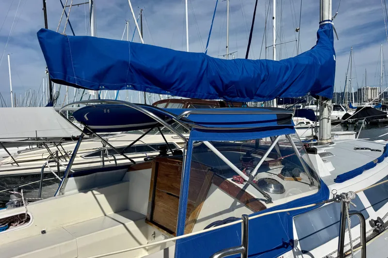 Slide: The Image of 1987 Catalina 34 sailboat with blue cover docked at marina. - 4