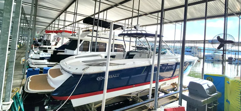 Slide: The Image of 2007 Cobalt 343 boat docked in a marina under a covered structure. - 2