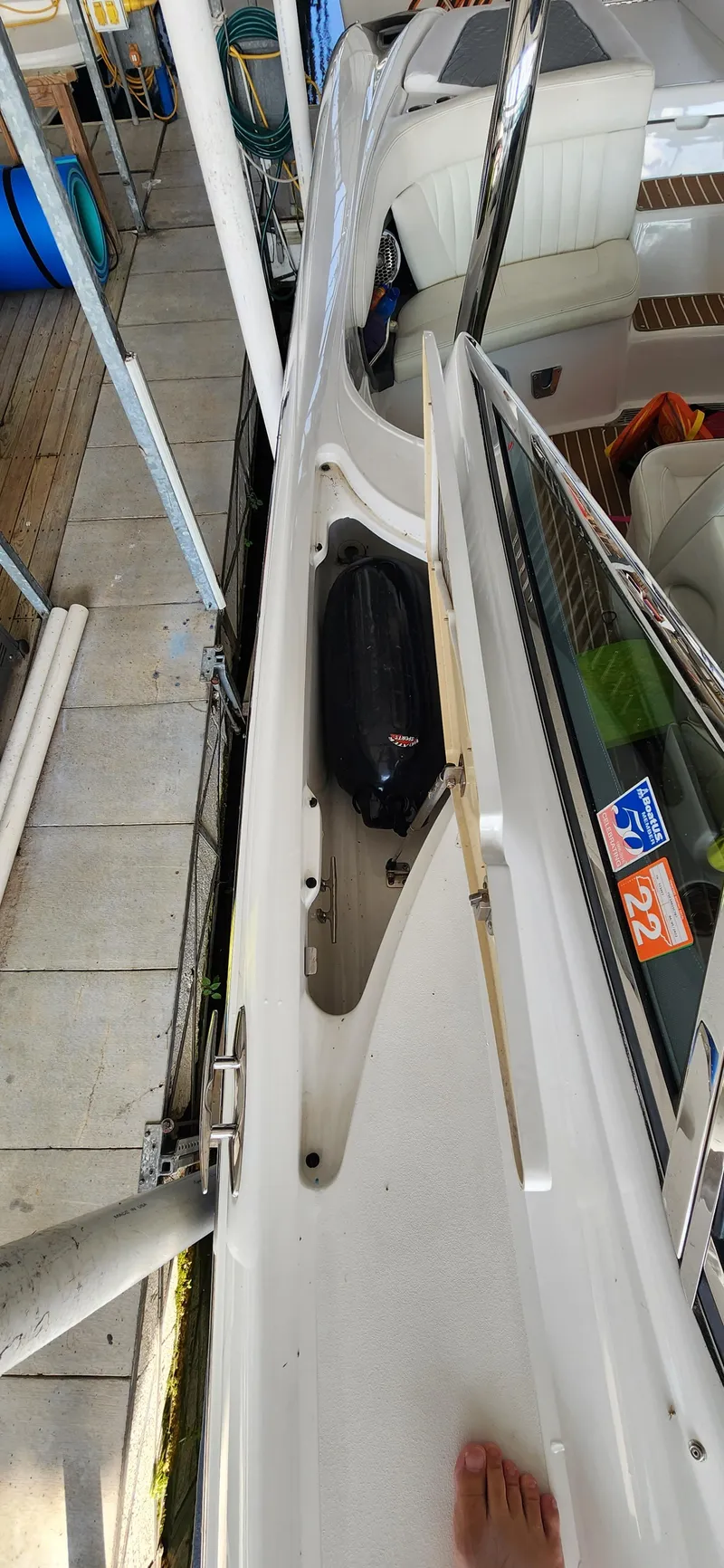 Slide: The Image of 2007 Cobalt 343 boat deck with storage compartment and visible dock surroundings. - 20