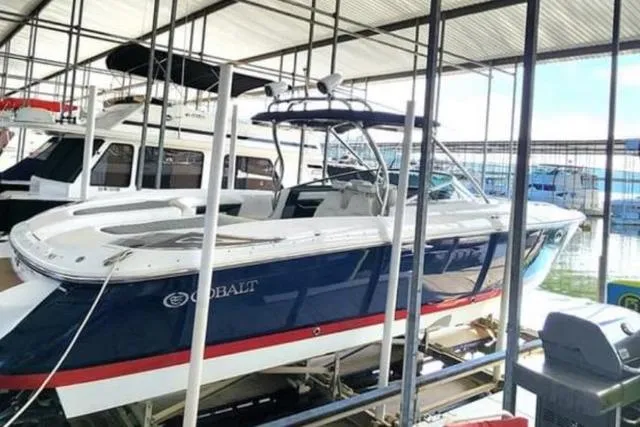 Slide: The Image of 2007 Cobalt 343 boat in marina, blue and white exterior, docked under shelter. - 42