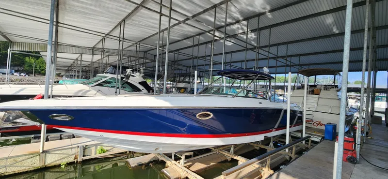 Slide: The Image of 2007 Cobalt 343 boat in marina, blue hull with red stripe, under covered dock. - 8