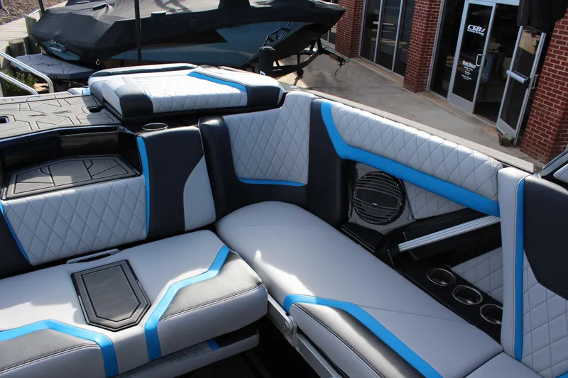 Slide: The Image of 2023 Tigé 23ZX boat interior with blue and white quilted seating and cup holders. - 11