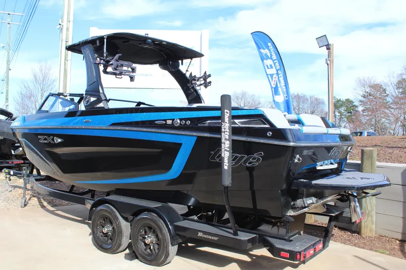 Slide: The Image of 2023 Tigé 23ZX boat with blue and black design on a trailer, displayed outdoors. - 3