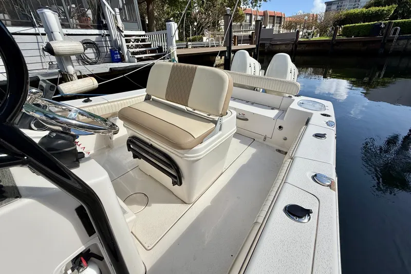 Slide: The Image of 2018 Sea Chaser 24 HFC boat interior with seating and steering wheel, docked by water. - 14