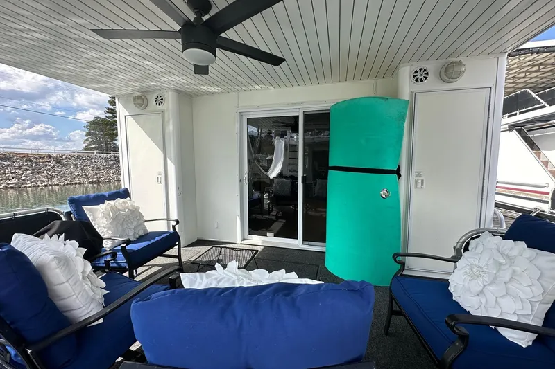 Slide: The Image of Outdoor seating area on a 2004 Sumerset 16x82 houseboat with blue cushions and ceiling fan. - 18