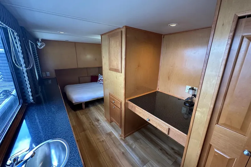 Slide: The Image of 2004 Sumerset 16x82 houseboat interior with wood paneling, bed, and countertop. - 6