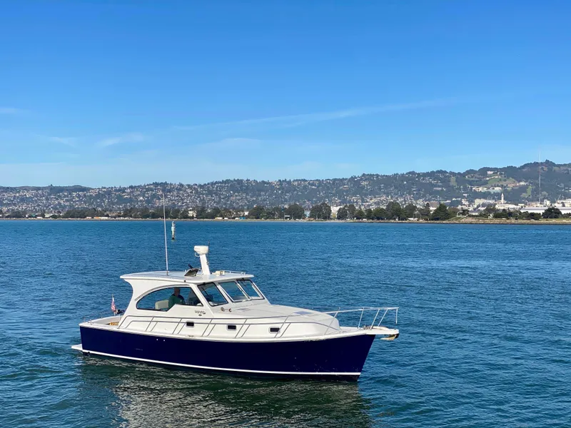 The Image of 2000 Mainship Pilot 34 on calm waters with coastal backdrop. - 0