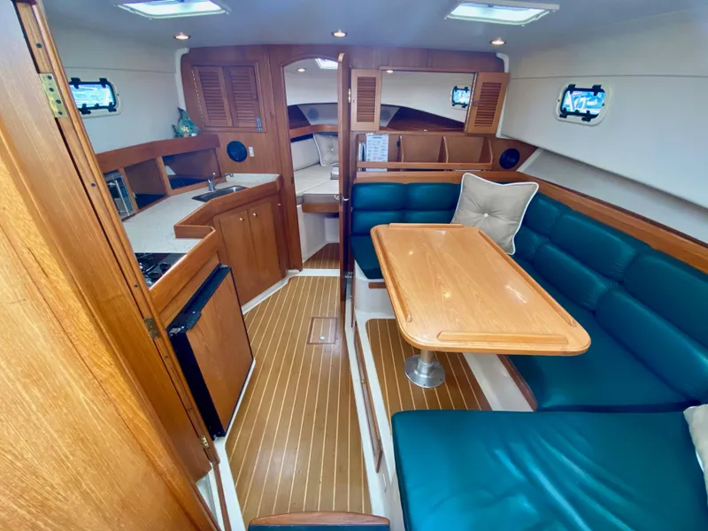 Slide: The Image of Interior of a 2000 Mainship Pilot 34 yacht with wood furnishings and blue upholstery. - 17