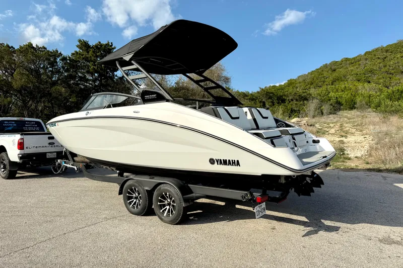 Slide: The Image of 2025 Yamaha Boats 252SE on trailer, parked outdoors under clear blue sky. - 10