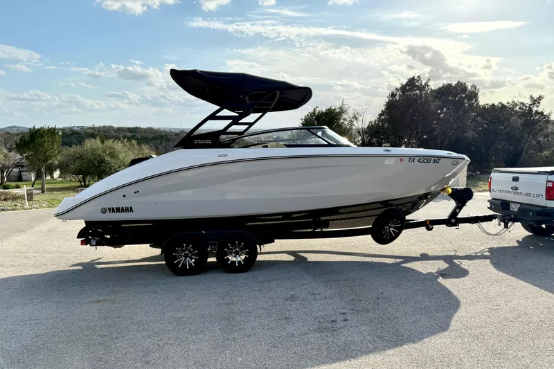 Slide: The Image of 2025 Yamaha Boats 252SE on trailer, parked outdoors under a clear sky. - 13
