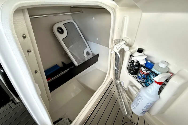 Slide: The Image of Interior storage compartment of 2025 Yamaha Boats 252SE with cleaning supplies and accessories. - 28