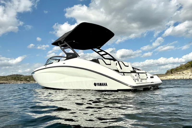 Slide: The Image of 2025 Yamaha Boats 252SE on water, sleek design, under a partly cloudy sky. - 5