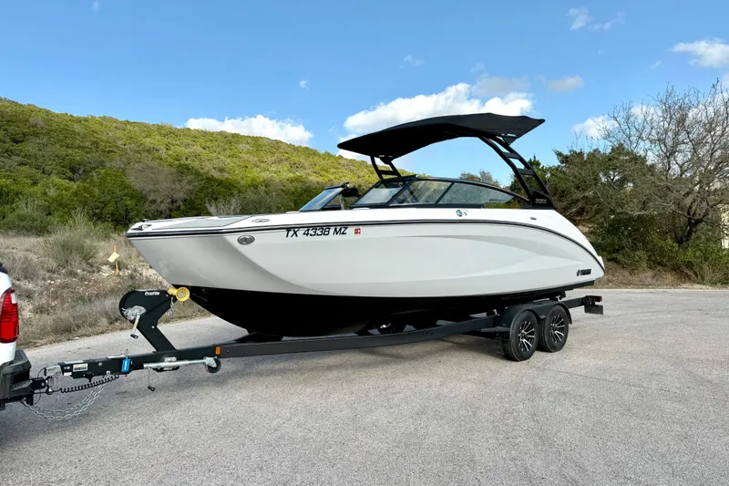Slide: The Image of 2025 Yamaha Boats 252SE on trailer, parked on road with scenic background. - 8