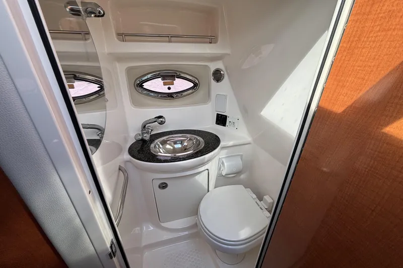 Slide: The Image of 2007 Chaparral Signature 250 boat bathroom with sink, toilet, and porthole window. - 34