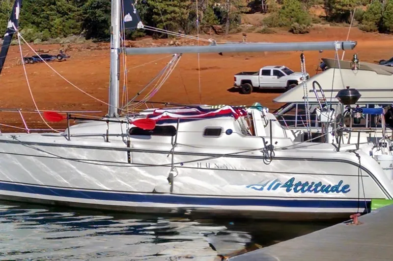 Slide: The Image of 2008 Hunter 27 sailboat docked on a serene lake with forested hills. - 2